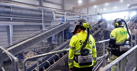 Two Syklo's employees are watching over sorting line activities infront of them.