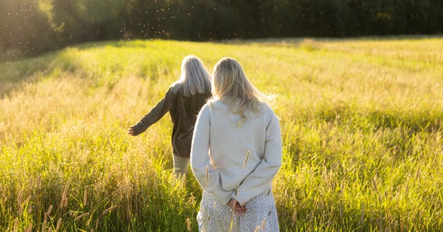 Two young women are running on a field on a sunny day.