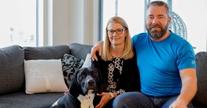 Family Alajoki is sitting on a couch. A dog is sitting on the floor.